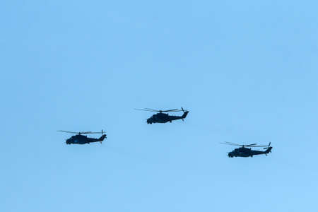 The flight of three soviet battle helicopters, type MIL Mi-24 flying on the bright blue sky.の写真素材