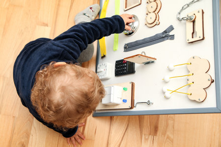 The small child plays with the activity board to gain new experience, practice his skills and get an improvement during his growth.の写真素材