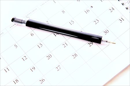 black pen laying on calanderの写真素材