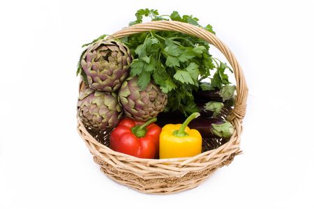 Vegetables - Basket with artichokes, eggplants, peppers and parsley isolated on white background.の写真素材