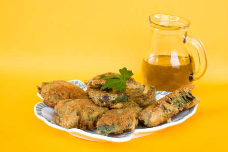 Food Recipes - First courses - Italian fried artichokes and jar with olive oil isolated on yellow background.の写真素材