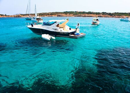 Petra Ruja Cove, Sardinia Coast, Italy, August 10, 2009 - People with boats enjoying the sunny day and the beautiful sea with transparent blue waters at Petra Ruja.のeditorial素材