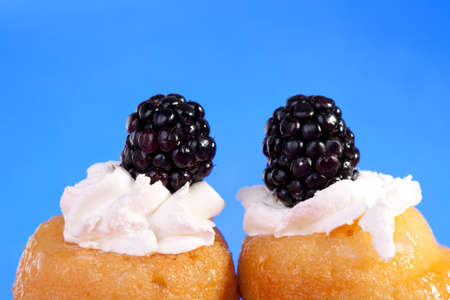 Macro of mignon, cakes decorated with whipped cream and blackberries 