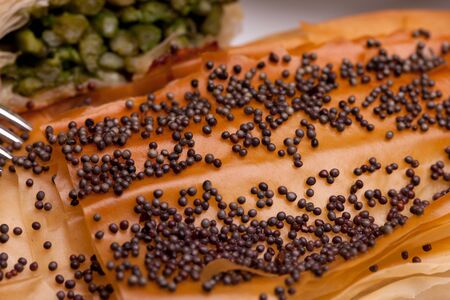 Closeup of crust with poppy seeds on top of asparagus rolls.の写真素材