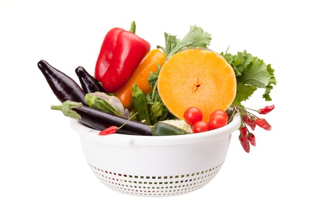 Colander with mix of vegetables isolated on white background の写真素材