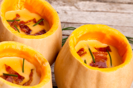 Cream of butternut squash and potatoes soup decorated with bacon and chives.の写真素材