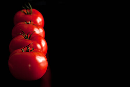45 degrees angle shot of tomatoes raw on black background の写真素材