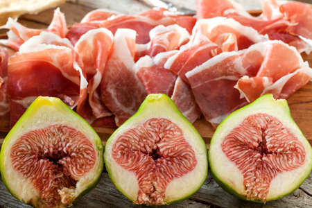 Fresh figs with ham on a white plateの写真素材