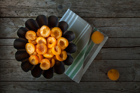 Apricot halves with sugar syrup in black bowl, above view.の写真素材