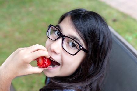 Cute Caucasian girl biting a strawberry.の写真素材