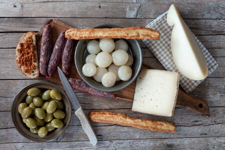 Overhead shot of assorted italian cheese (caciocavallo and Bastardo cheese), smoked sausages, cipolle borettane ( a variety of pickled onions), green olives and bruschetta with chili peppers sauce.の写真素材