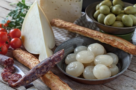Assorted italian cheese (caciocavallo and Bastardo cheese), smoked sausages, cipolle borettane ( a variety of pickled onions), green olives, cherry tomatoes and bread sticks.の写真素材