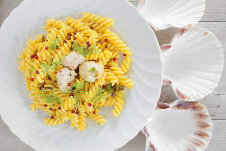 Fusilli pasta with scallop cream garnished with red peppercorns and dill.の写真素材