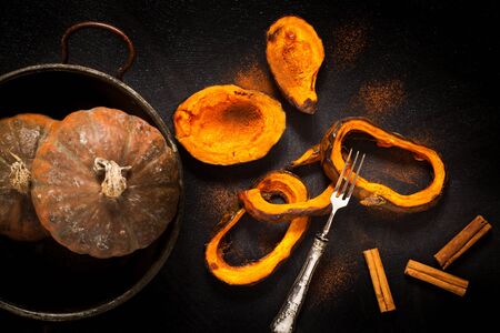 Baked pumpkin slices with cinnamon over black background, top view shot.の写真素材