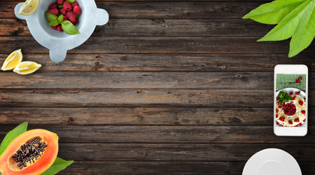 Fresh fruits frame with customizable smartphone on wood background, top view with copy space. の写真素材