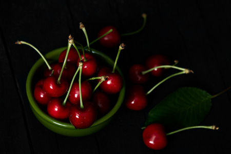 Bowl with fresh cherries on black background.の写真素材