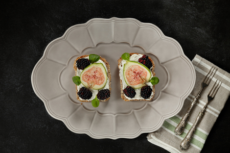 Plate with toasts made by wholemeal bread, cream cheese, blackberries and figs, flat lay.の写真素材