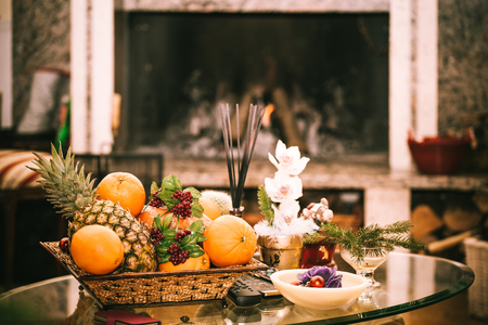 Cozy warm atmosphere inside living room with fireplace, fruits and flowers on the table.の写真素材