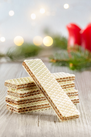 Stack of wafer biscuits filled with hazelnuts cream with winter holidays lights bokeh in the background.の写真素材