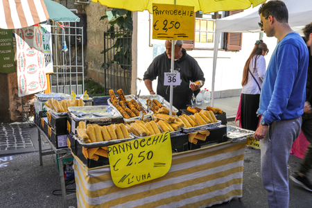 MANZIANA, LAZIO, ITALY - OCTOBER 14, 2017: Man buying grilled corn from street vendor at the chestnut festival.のeditorial素材