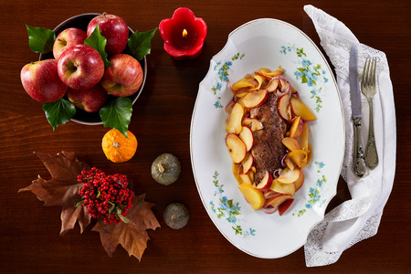 Roasted pork fillet with apples on white plate, typical fall-winter recipe. Photographed from above.の写真素材