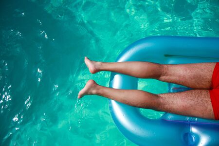 Sunbathing in the pool - Top view of half body of a man on an inflatable matress in a poolの写真素材