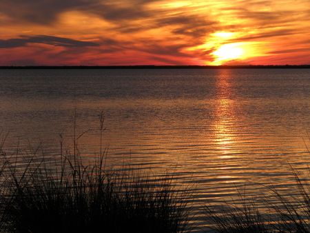 Orange sunset over water and marsh grassの写真素材