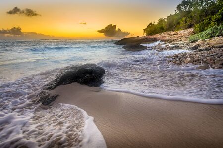 Dramatic Caribbean sunset with stop-action waves and rocky outcrops