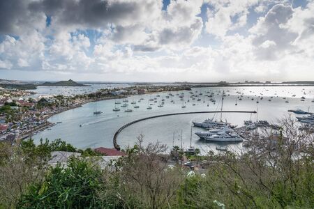 A scene overlooking a bay containing sailboats and ships