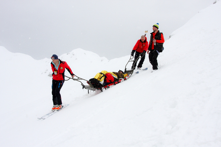 Oslea HiRide 2015 - Team of three mountain ski rescuers transporting an accident victim on a sledge stretcherのeditorial素材