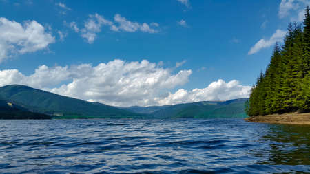 Clouds and green mountain forest - view from the surface of the lakeの写真素材