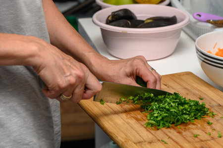 woman cutting parsley on a cutting board in the kitchenの写真素材