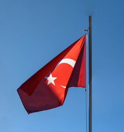 Turkish flag waving in the wind against the blue sky. Flag of Turkey