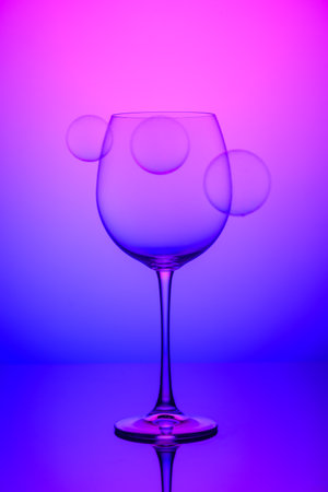 wine glass with soap bubbles on blue and pink backgroundの写真素材