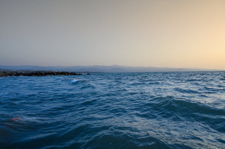 Warm waves of the Mediterranean sea and a sandy beach at sunrise