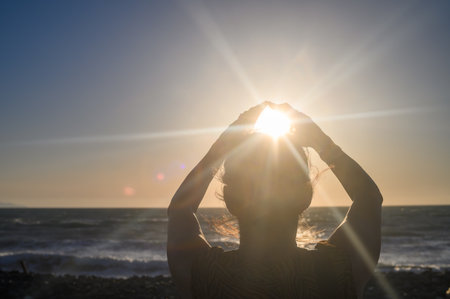 Silhouette of a woman holding the sun in her hands 2