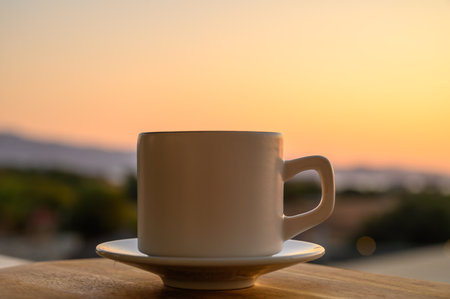 cup of black coffee over wood table and Sunset