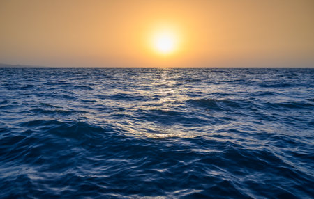 Warm waves of the Mediterranean Sea and sandy beach at sunset