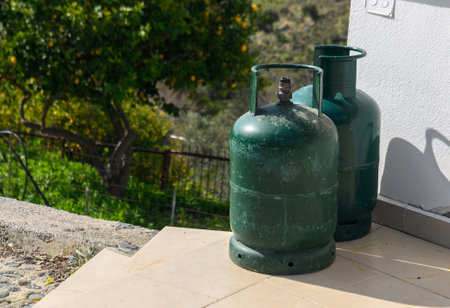 green gas cylinders stand in a row near a house on the street.の写真素材