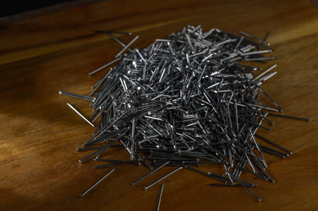 A pile of small nails on a wooden tableの写真素材