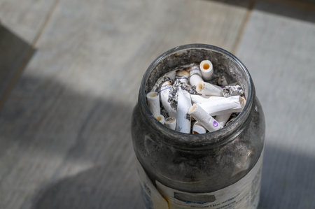glass jar filled with many cigarette buttsの写真素材