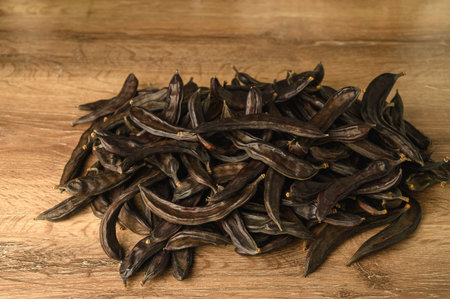 Carob pods and carob beans on the wooden table.の写真素材