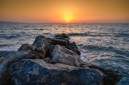 Sunset seascape with rocks and sea pebbles, travel background, tourist locationの写真素材