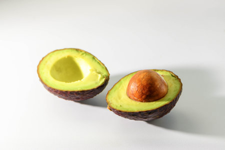 Freshly Cut Avocado Halves with Pit on White Background