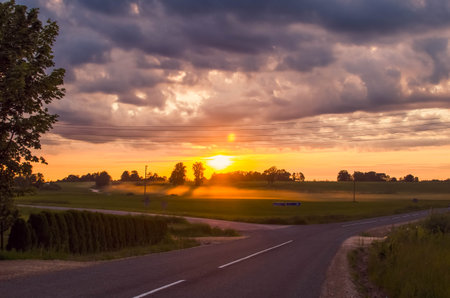Road in autumn morning, sunrise in background