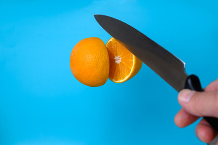 a knife cuts an orange in the airの写真素材