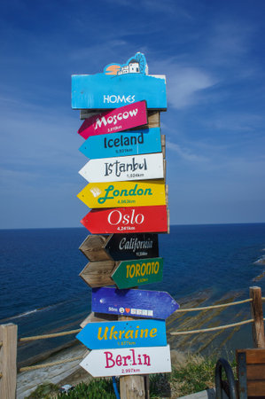 Nestled along the coast, a vibrant signpost offering directions to major cities worldwide, with...