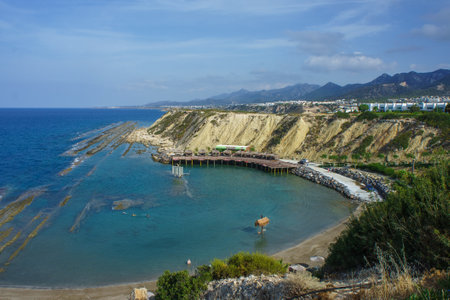 The tranquil bay, framed by rugged cliffs, features clear turquoise waters lapping against the shore under a bright blue sky, inviting exploration and relaxation.の写真素材