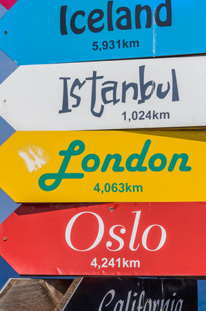 A directional vibrant signpost displays distances to various iconic cities, inviting travelers to...
