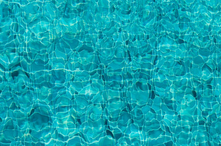 Turquoise water ripples gently in the sunlight, reflecting an array of vibrant hues and creating an...
